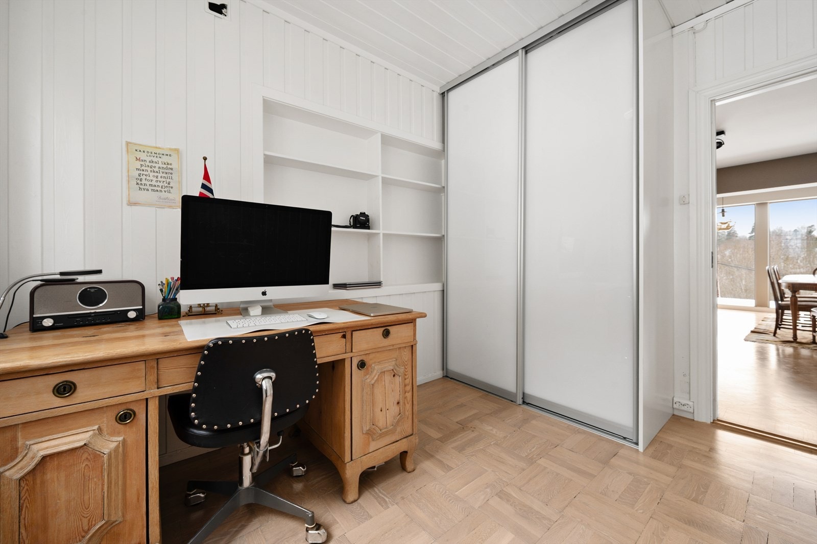 Et romslig kontor med plass til fullverdig arbeidsstasjon. Skyvedørsgarderobe sørger for smart og plassbesparende oppbevaring Galleribilde