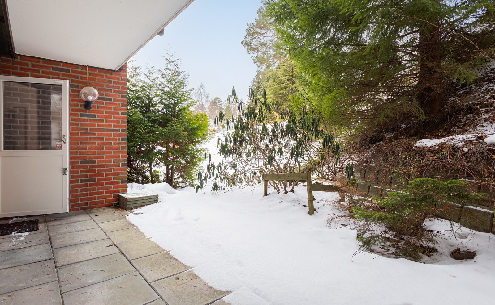 Fra kjøkkenet er det utgang til en stor og lun markterrasse, skjermet av frodig beplantning Galleribilde