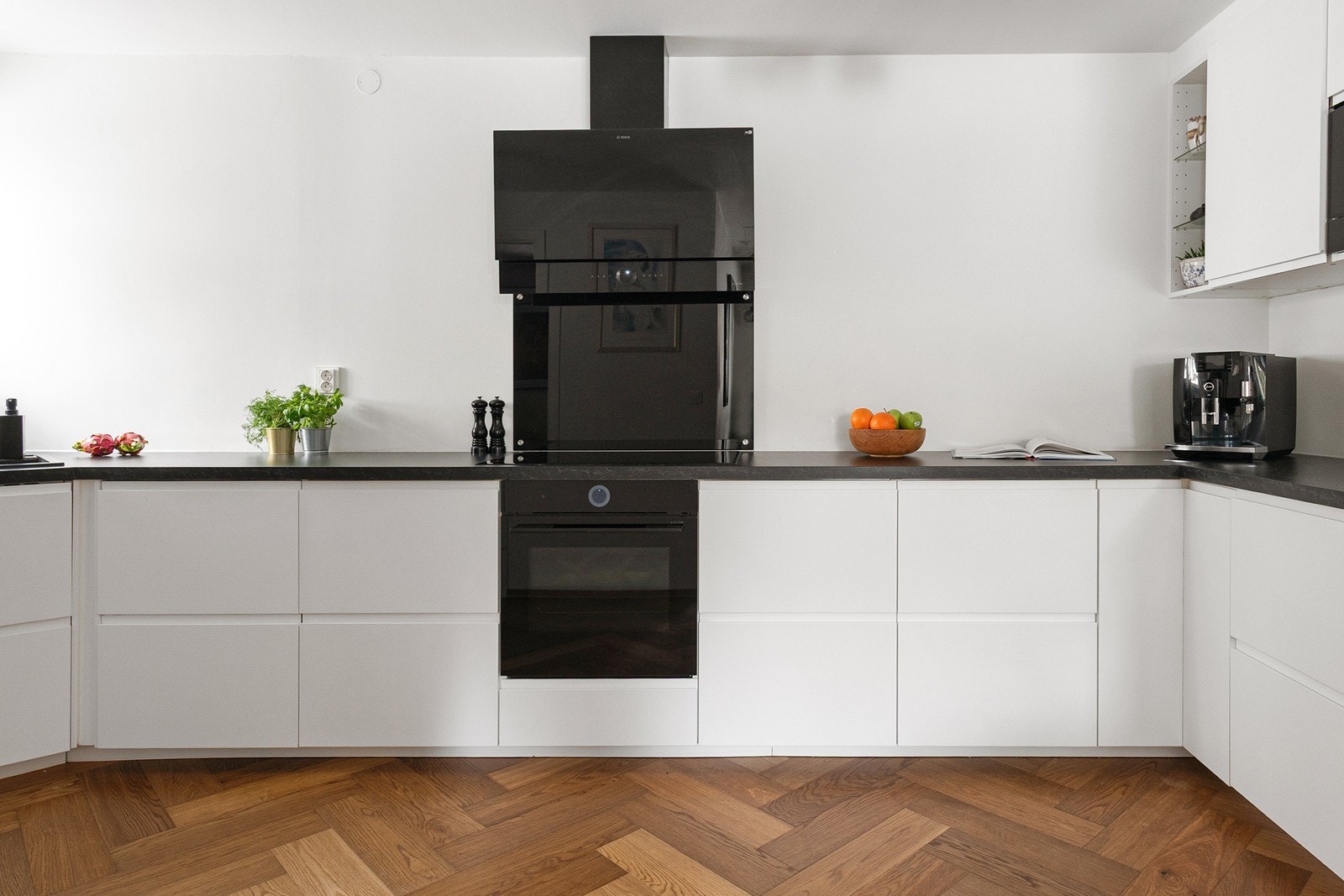 Kjøkkeninnredningen har slette fronter, store arbeidsflater og gode oppbevaringsmuligheter. Stillegående ventilatorhette i glass med touch- og WiFi-funksjon Galleribilde