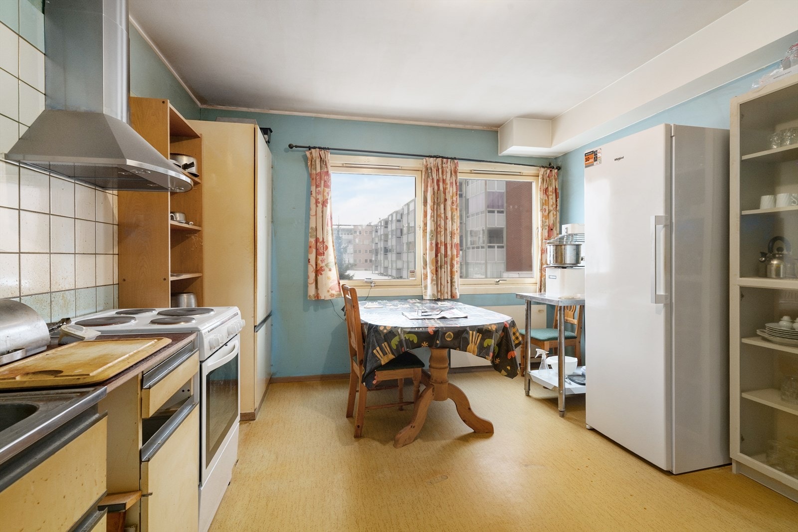 Kjøkken med fin spiseplass ved vindu og eldre kjøkkeninnredning fra byggeår. Galleribilde