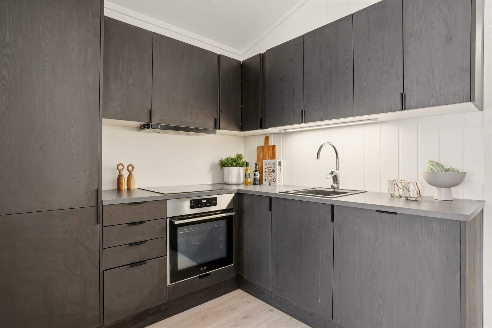 Integrerte hvitevarer og rene linjer gir et helhetlig uttrykk, samtidig som arbeidsflaten i L-form gjør matlaging både praktisk og oversiktlig. Galleribilde