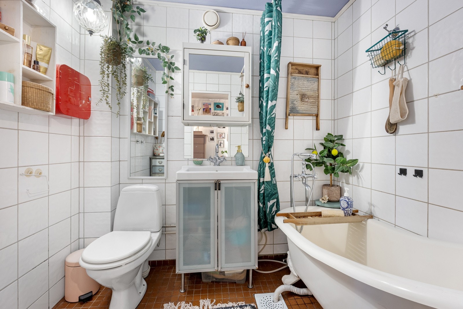 Flislagt bad utstyrt med badekar, servant med innredning, speilskap og wc. Galleribilde