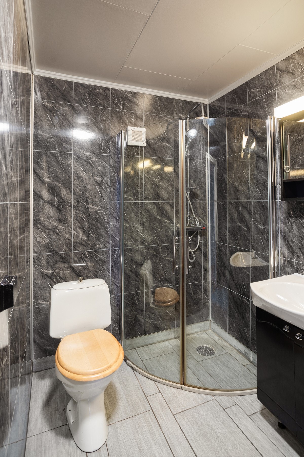 Badet har flislagt gulv med varmekabler, og våtromsplater på vegg. Badet er utstyrt med wx, dusjhjørne og servant med innredning. Galleribilde