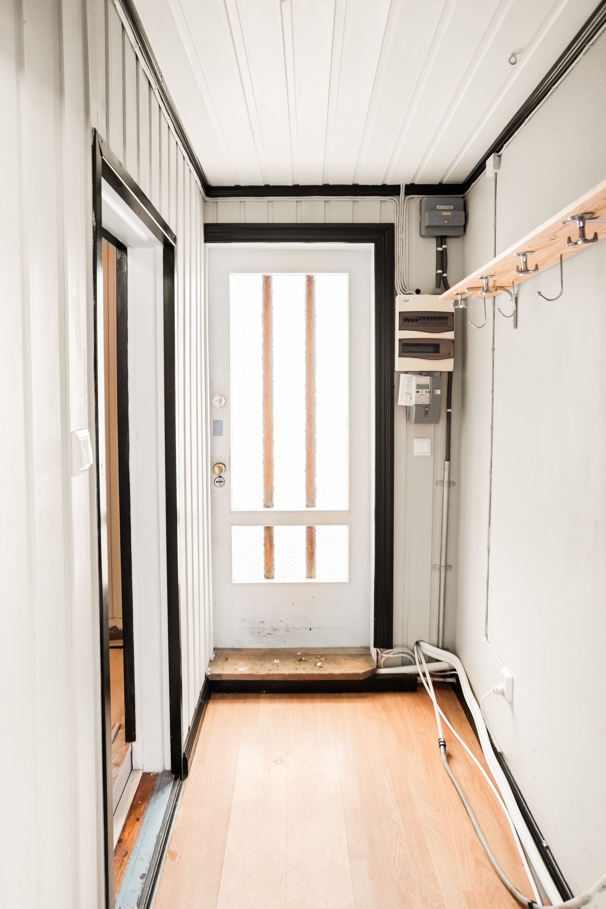 Entré med lyse vegger, paneltak og laminatgulv. Vegghengt knaggrekke og sikringsskap ved døren. Galleribilde