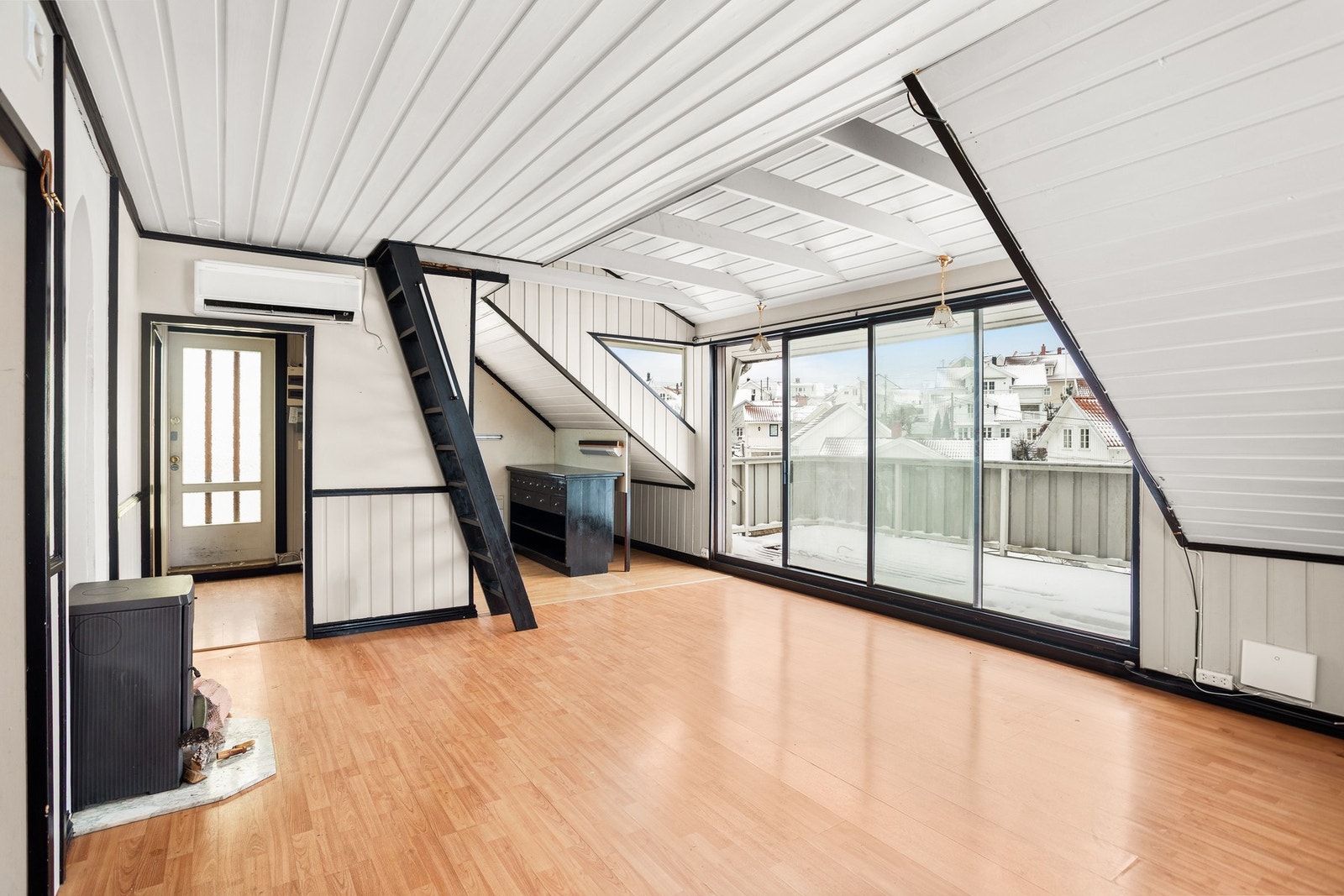 Lyst rom med store vinduer og utgang til balkong. Skråtak gir karakter, og det er en trapp til hemsen. Galleribilde