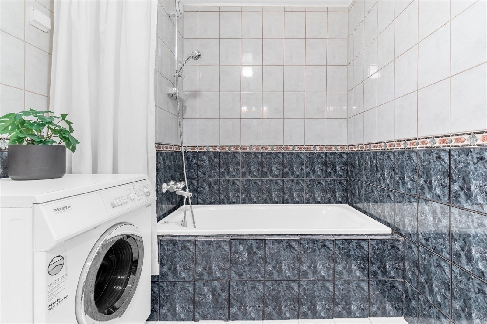 Det har servant med speil over, badekar og opplegg for vaskemaskin. Baderomsinnredningen har profilerte fronter som gir et klassisk og pent uttrykk. Galleribilde