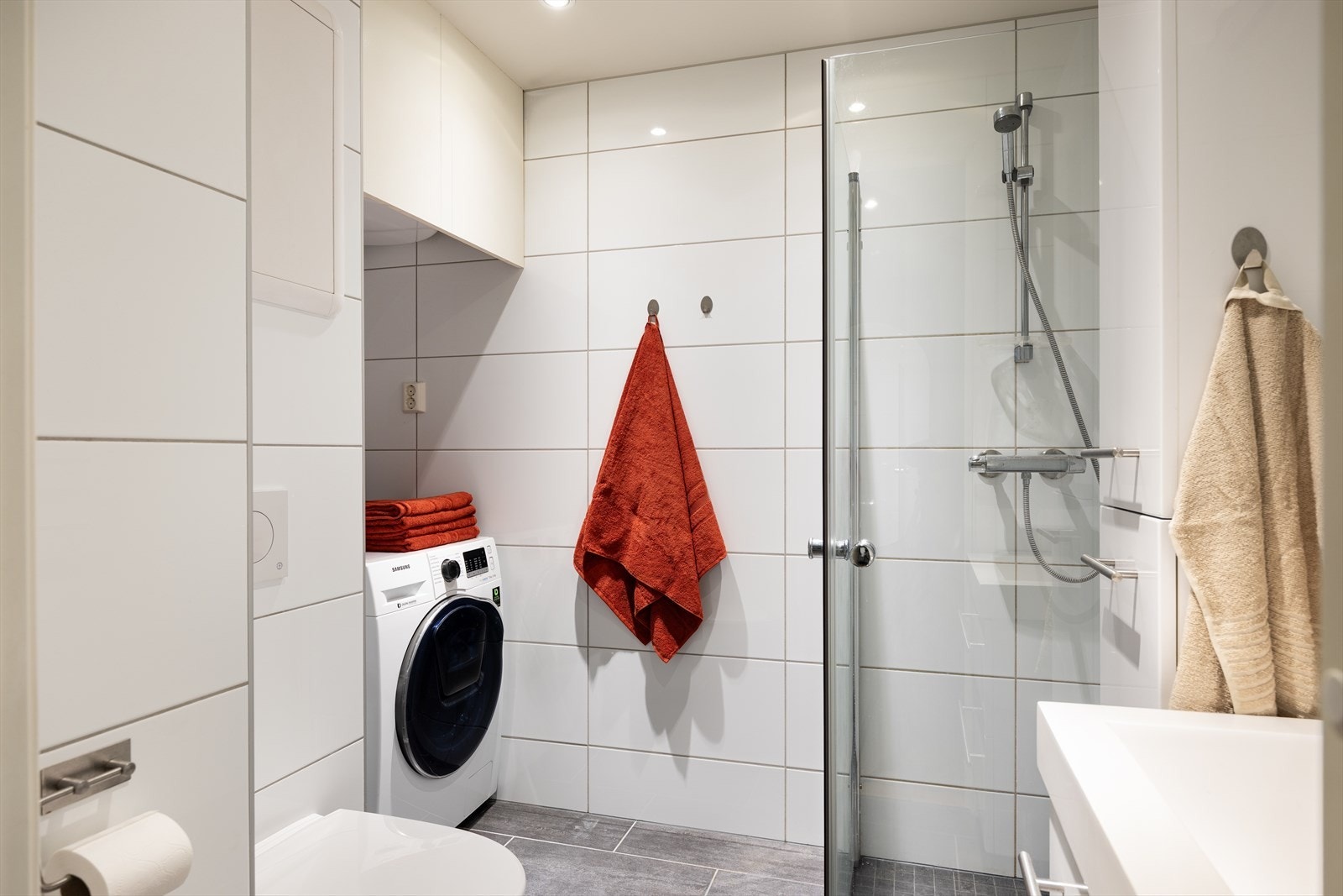 Badet er utstyrt med mekanisk avtrekk, rørfordelingsskap, innfellbare dusjdører, veggmontert wc, bereder og opplegg for vaskemaskin. Galleribilde