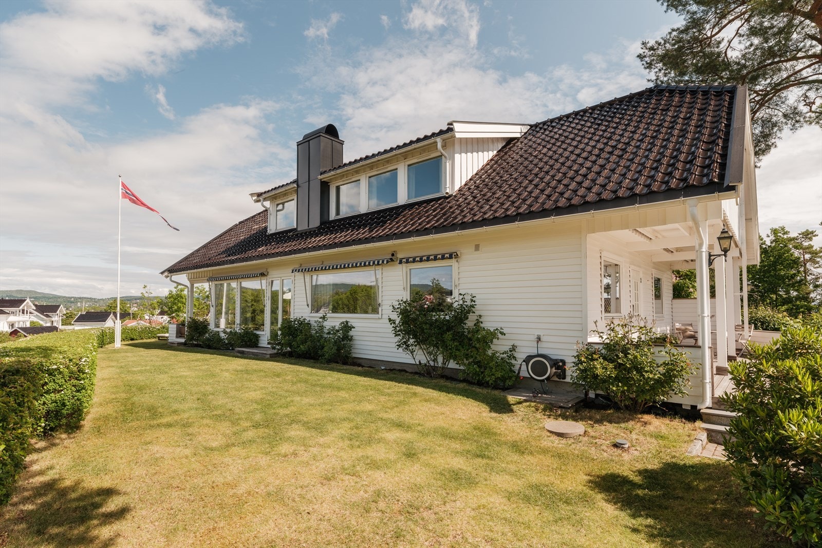 Tomten er romslig, solrik og pent opparbeidet med plen, prydbusker og blomstrende hekk. Galleribilde
