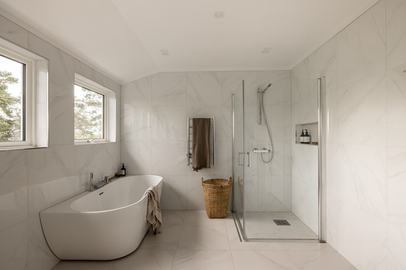 Badet er innredet med frittstående badekar, dusjhjørne med innfellbare glassdører og nisje for oppbevaring, vegghengt toalett og servantskap med doble servanter og profilerte fronter. Galleribilde