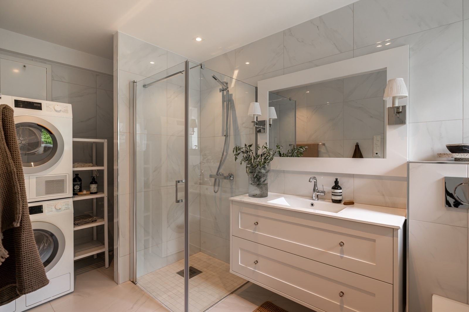 Lekkert og funksjonelt kombinert bad og vaskerom med gjennomført stil og moderne materialvalg. Galleribilde