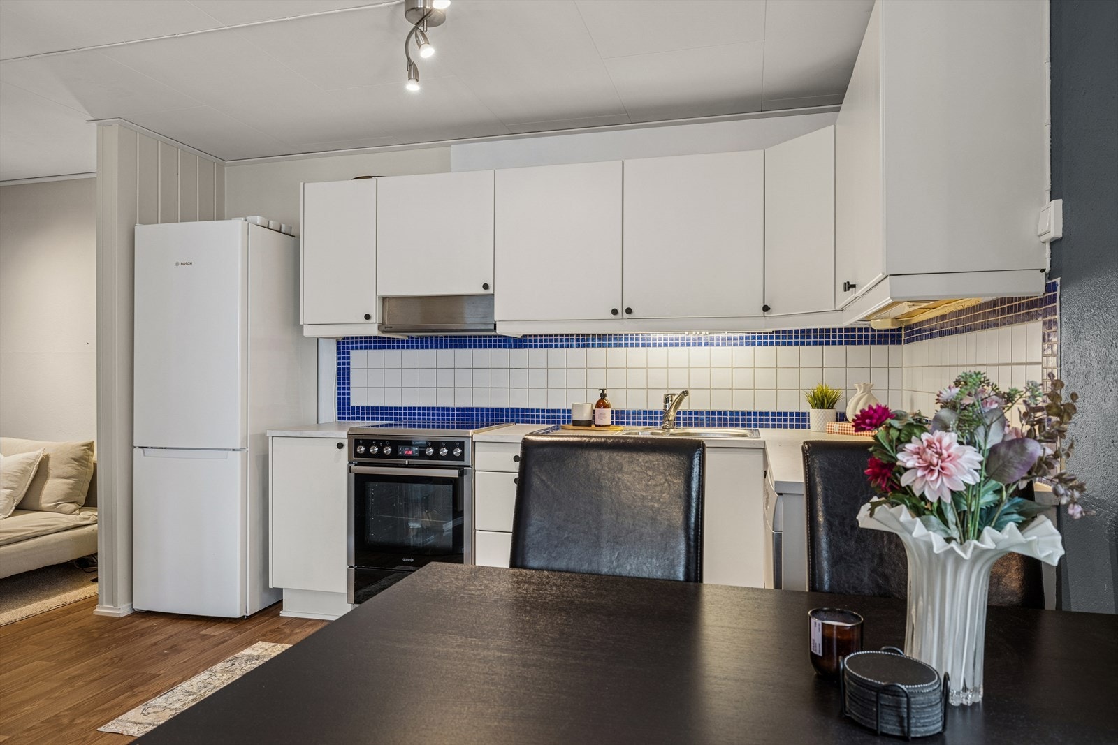 Kjøkkenet har innredning med slette hvite fronter og fliser mellom over- og underskap. Galleribilde