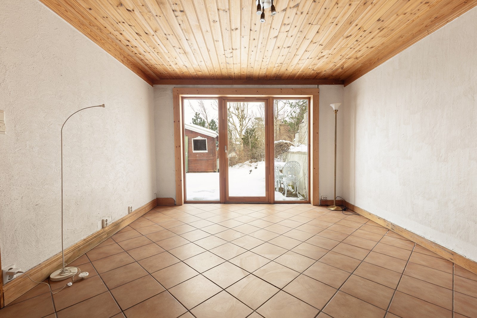 Rommet har flislagt gulv, trepanel i taket og utgang til hagen. Galleribilde