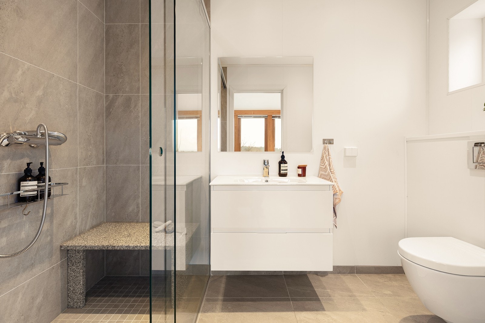 Her er det flislagt gulv med elektriske varmekabler, veggmontert toalett og dusjhjørne. Galleribilde