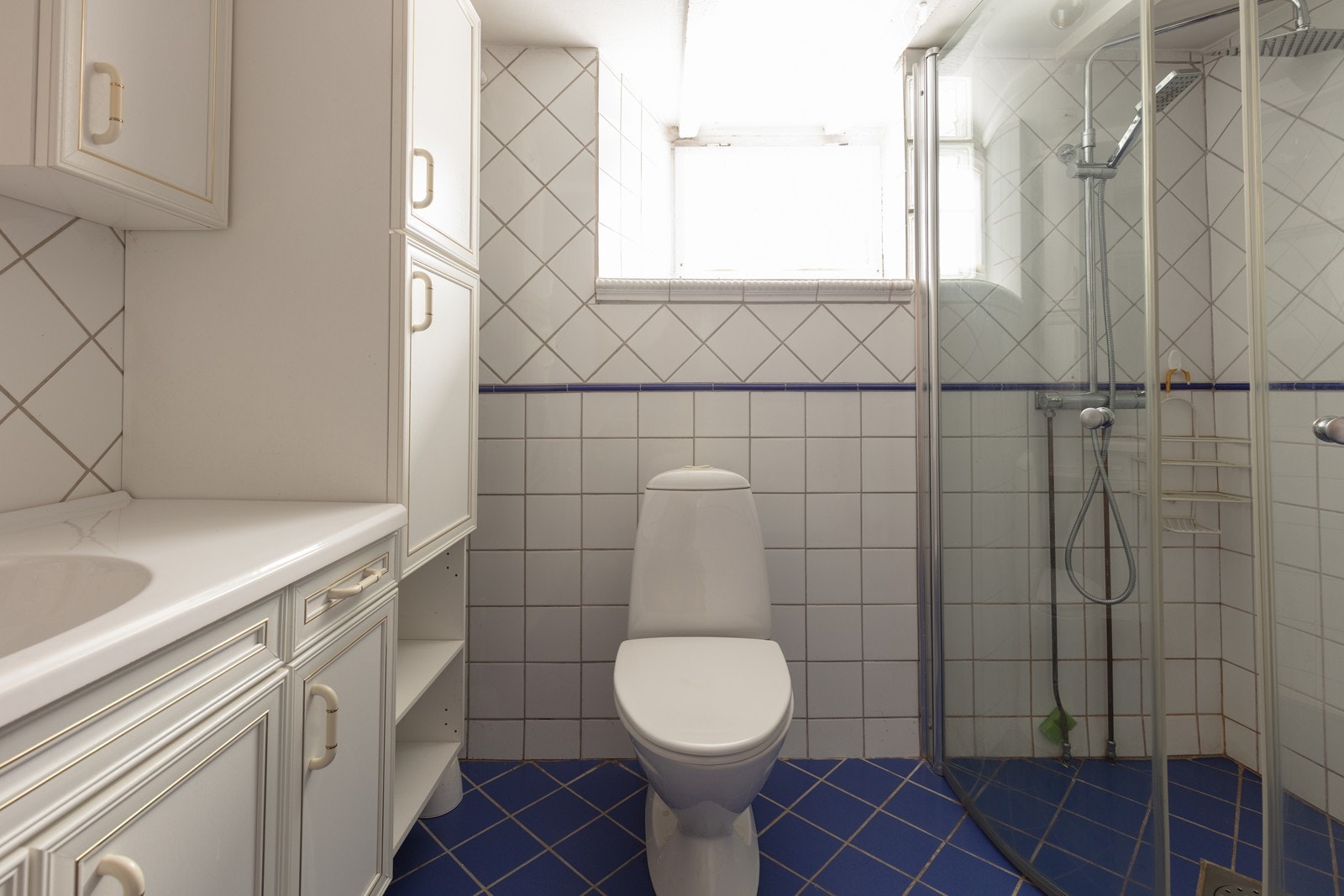 Boligen har bad i alle etasjer, inkludert dette flislagte badet i kjelleren med dusjhjørne. Galleribilde