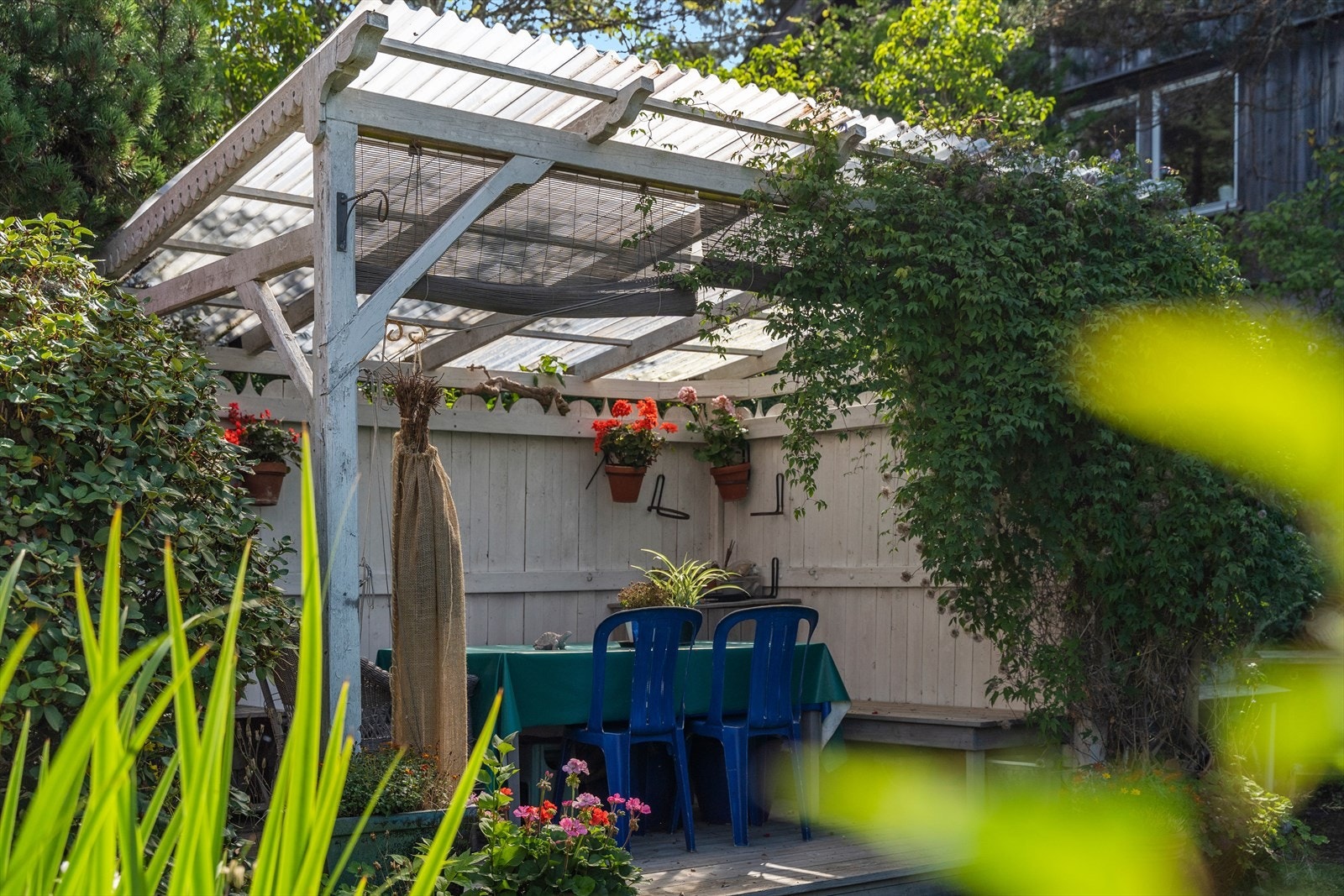 En overbygd uteplass i hagen gir ly for vær og vind. Galleribilde