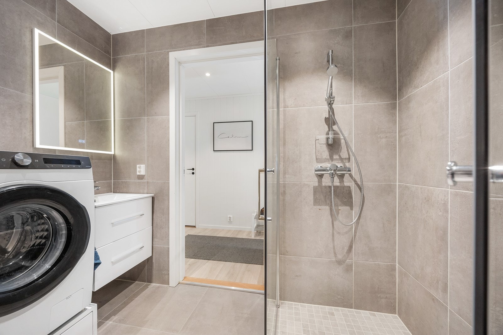 Innredningen har heldekkende servant over hvit skuffeseksjon og et speil med integrert lys. Galleribilde