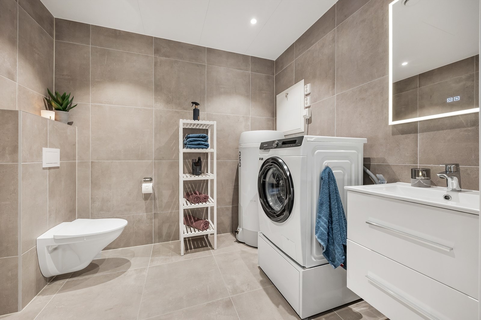 Badet er delikat og stilfullt - med store vegg- og gulvfliser i ulike, harmonerende fargetoner. Galleribilde