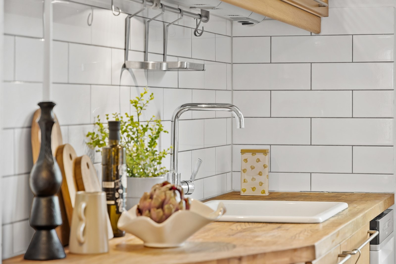 Benkeplaten suppleres av en hvit keramisk oppvaskkum og fliser over benken Galleribilde