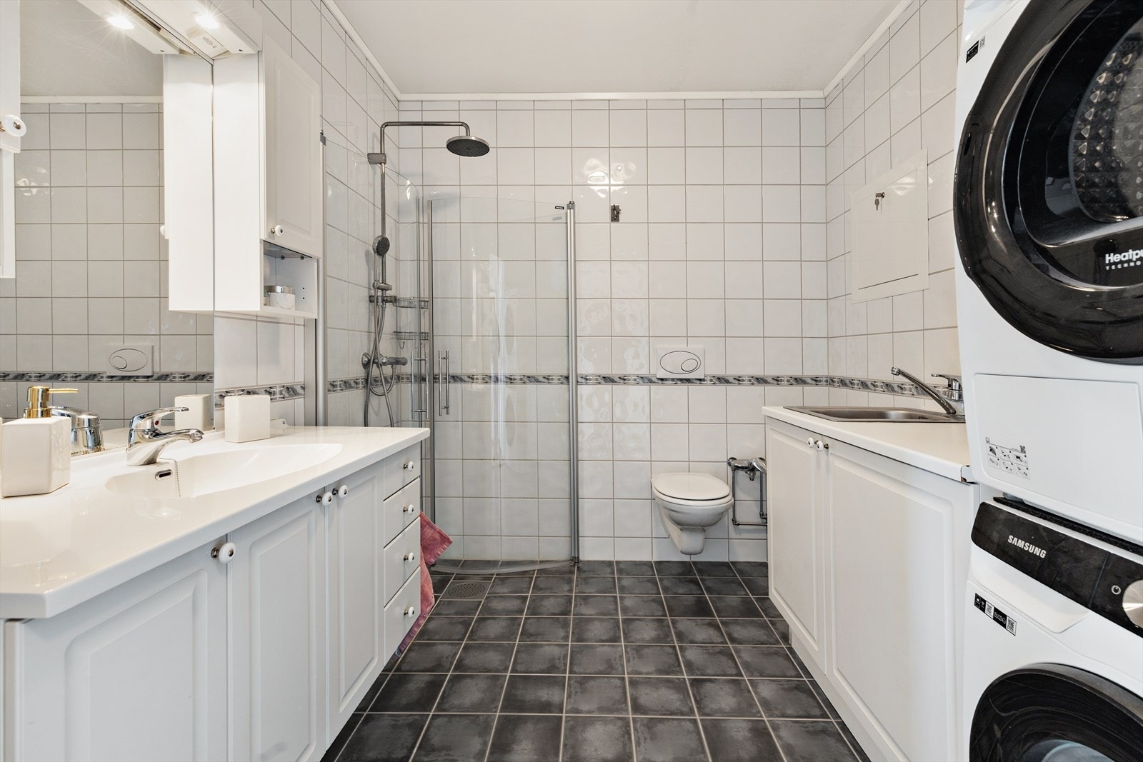 Innredningen består av servant, speil på vegg, belysning, vegghengt toalett, dusjsone og ekstra oppbevaringsplass. Galleribilde