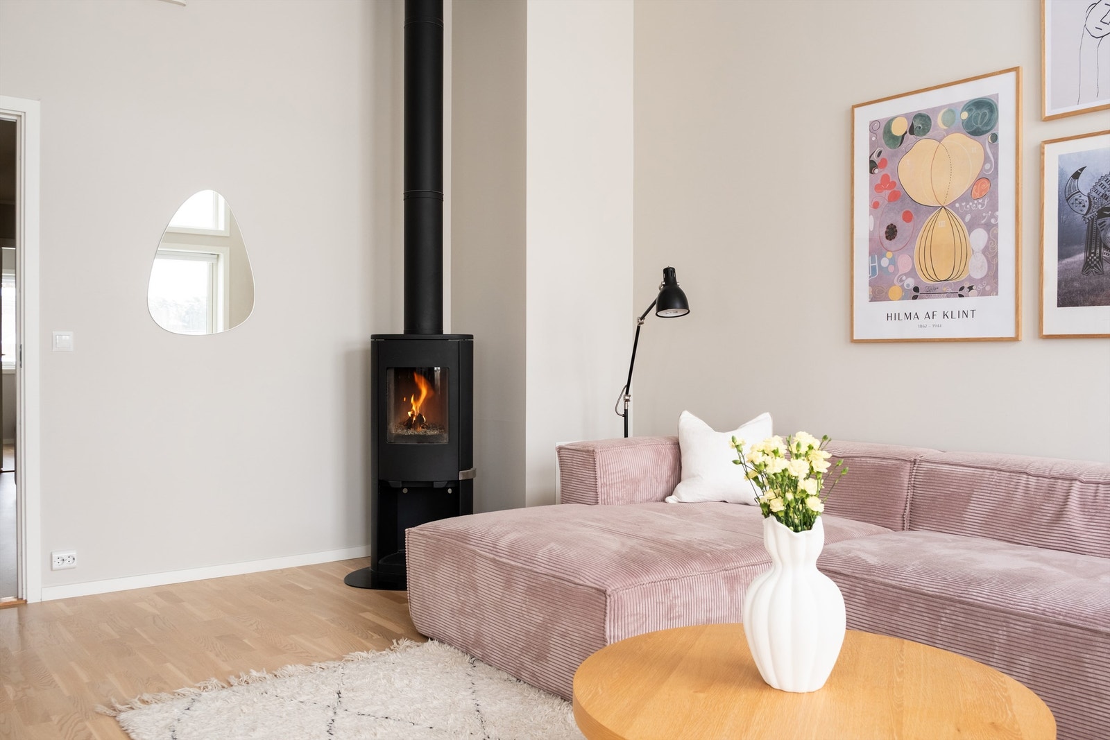 Lys stue med rolig fargepalett, rikelig dagslys og en sentral ovn som gir god stemning og varme. Galleribilde