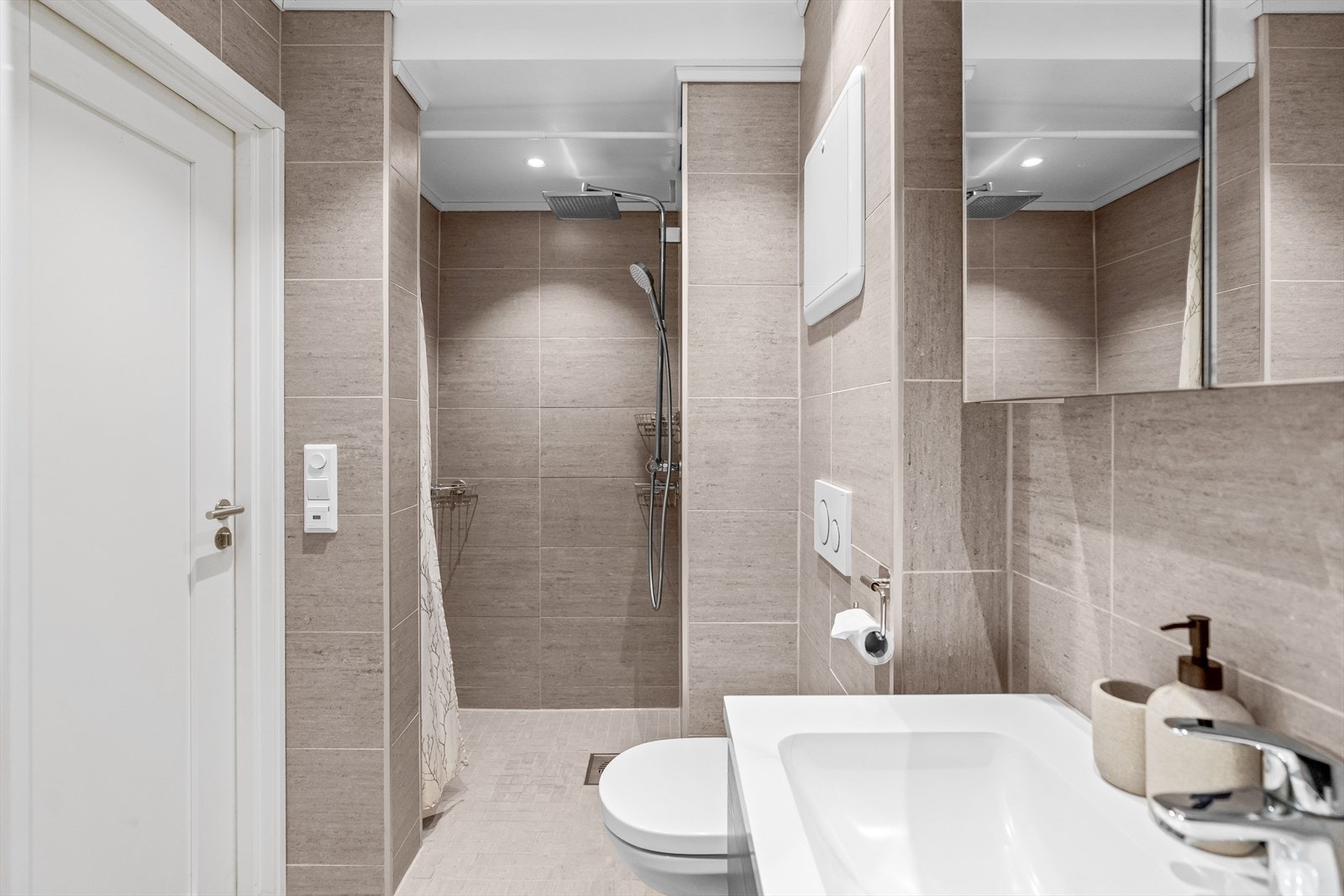 Det delikate badet har store grå fliser på gulv og vegger, downlights samt gulvvarme. Galleribilde