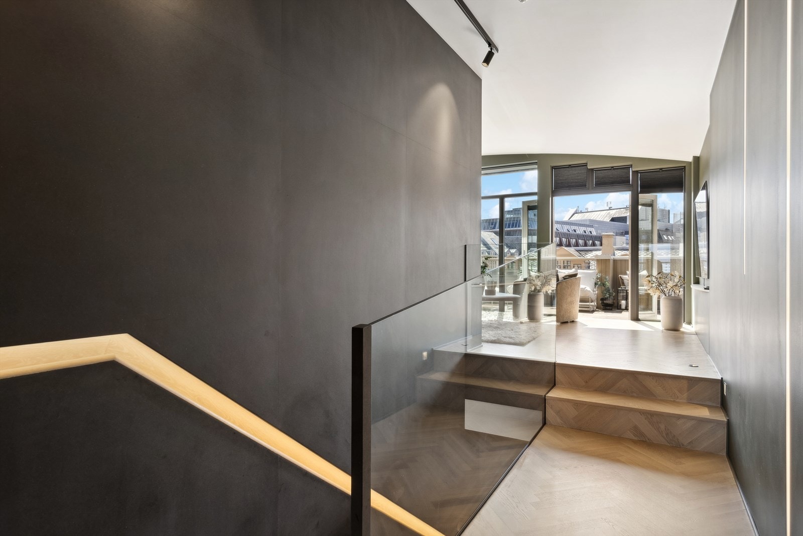 Det er valgt gjennomgående materialer som skal stå i stil med hverandre - det ser man på trappetrinn, håndløper og fiskebeinsparkett, samt sorte detaljer i kontrast til disse Galleribilde