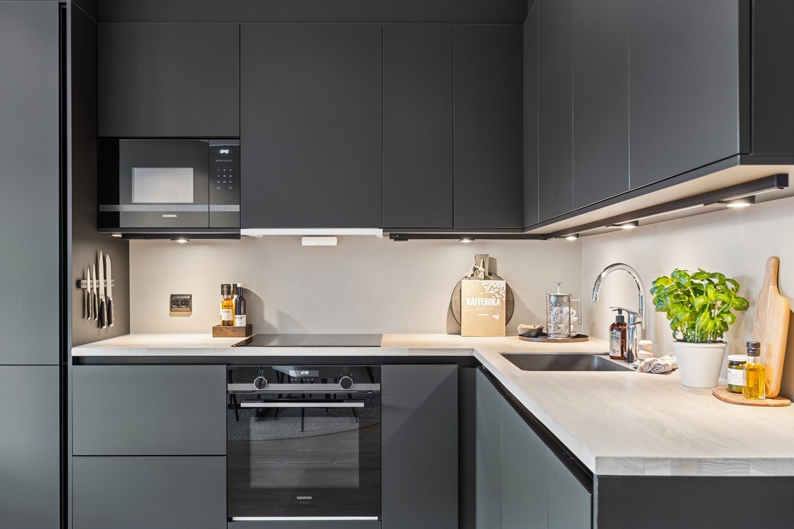 Kjøkkenet fremstår som stilrent med fronter i dempet sort, underlimt servant og benkeplate av Eik. Galleribilde