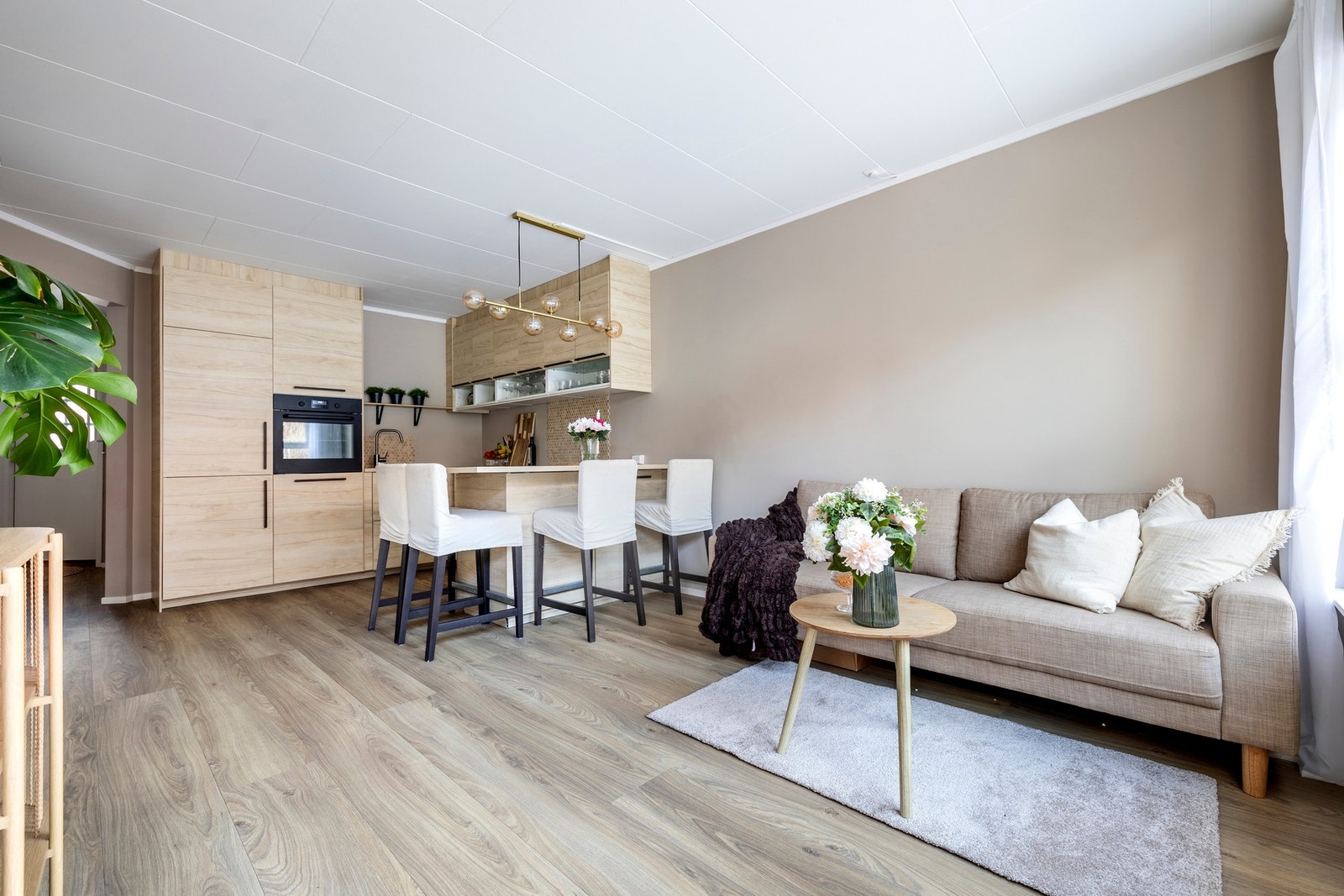 Leiligheten har en åpen stue-/kjøkkenløsning som danner et luftig og sosialt allrom. Stuen er malt i tidsriktige fargetoner og har laminatgulv. Galleribilde