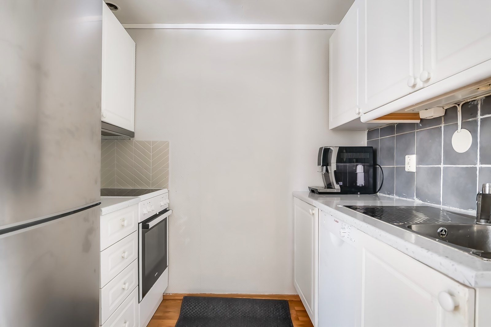 Kjøkkeninnredningen har hvite, profilerte fronter og plass til hvitevarer. Galleribilde