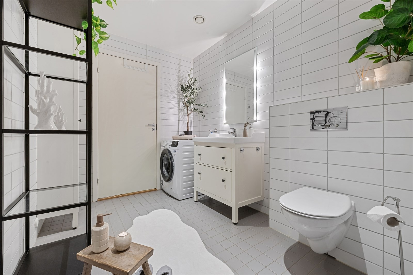 Flislagt bad med dusjhjørne, vegghengt toalett og gjennomført, moderne uttrykk. Galleribilde