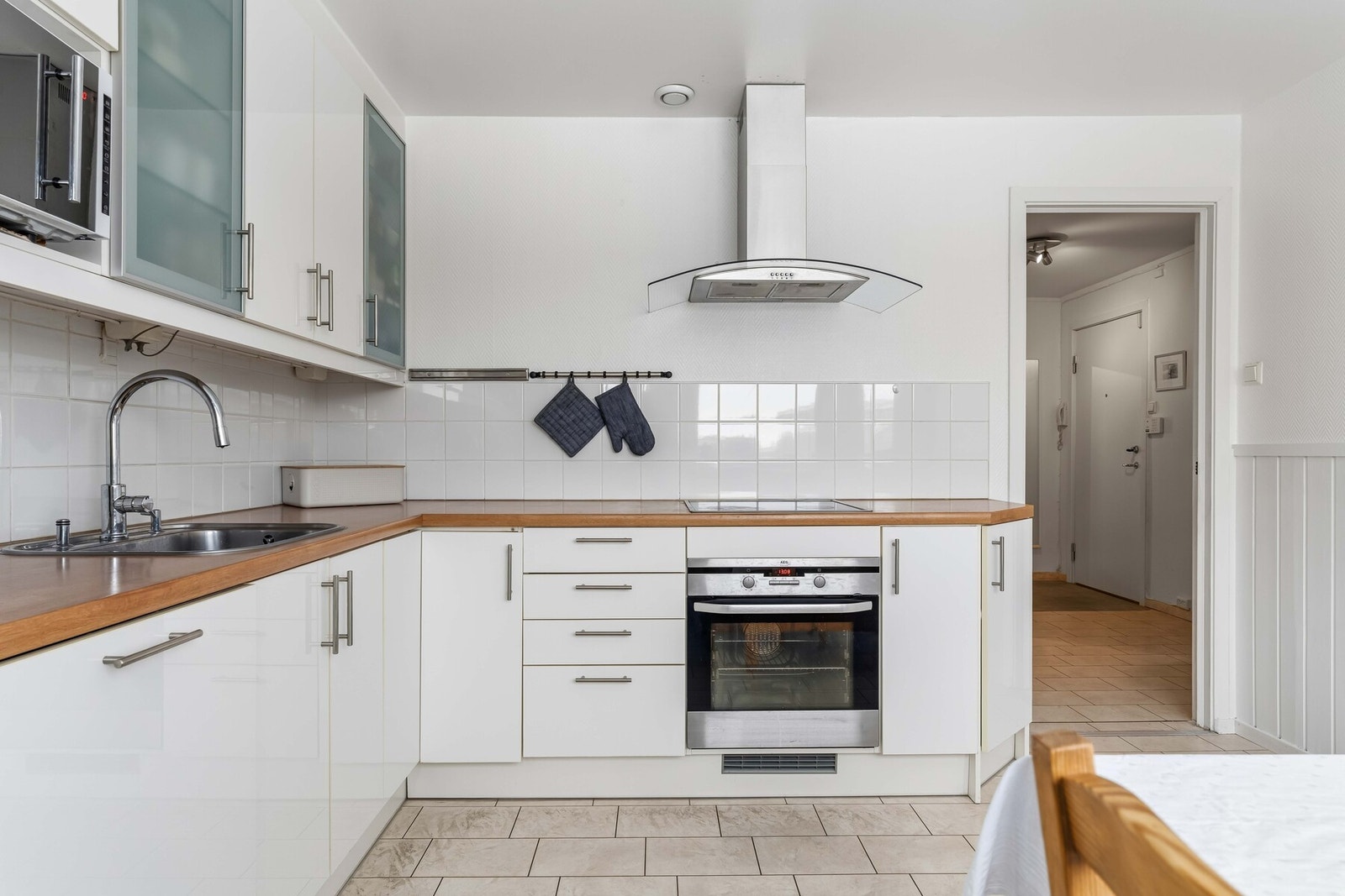 Innredningen har takhøye skap med høyglansede folierte fronter, 2 overskap med frostet glass og laminat benkeplate med oppvaskkum i stål Galleribilde