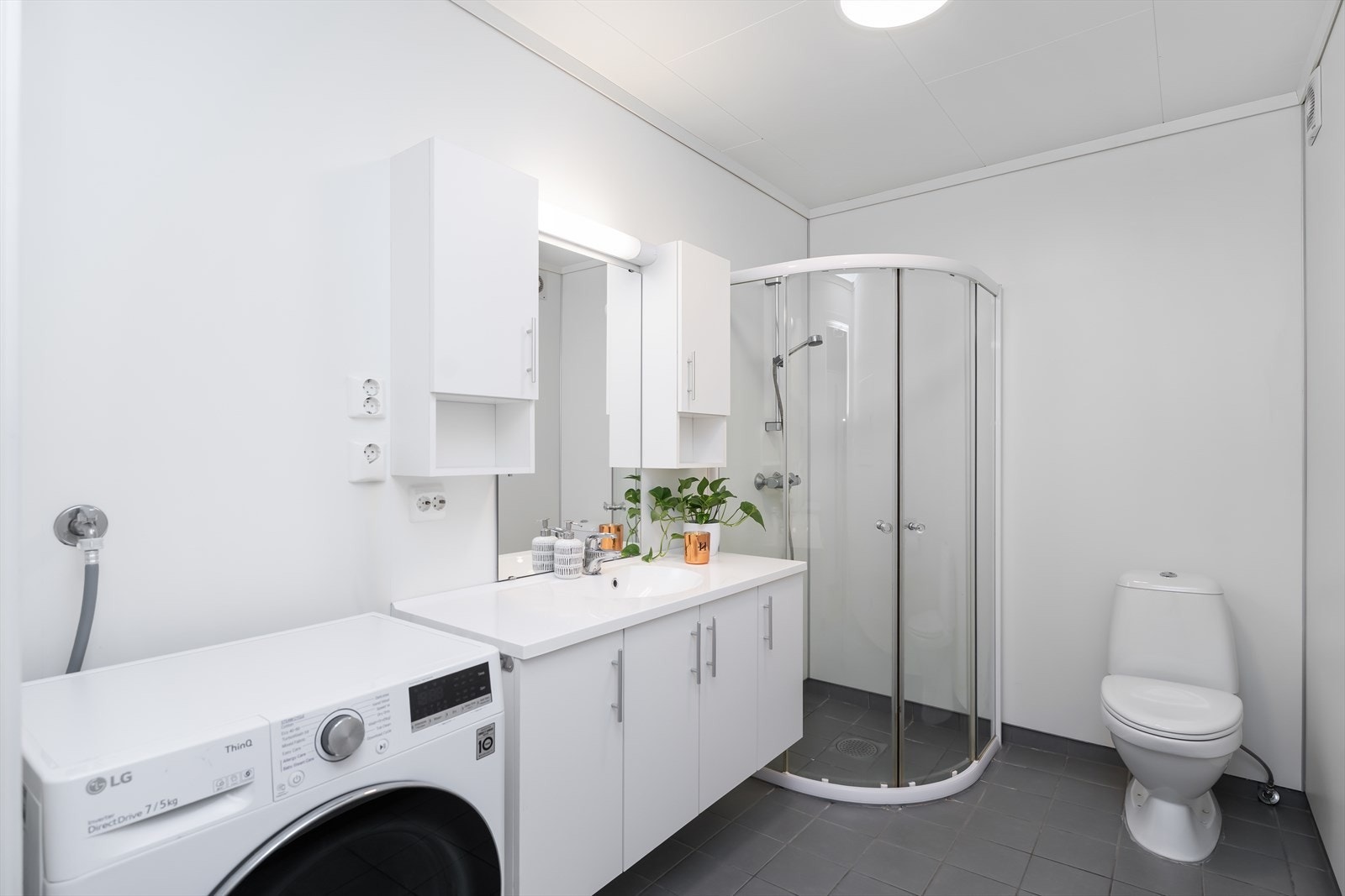 Bad med fliser på gulv og varmekabler. Her finner vi også dusjhjørne, toalett og baderomsinnredning med underskap og overskap for ekstra oppbevaring. Galleribilde