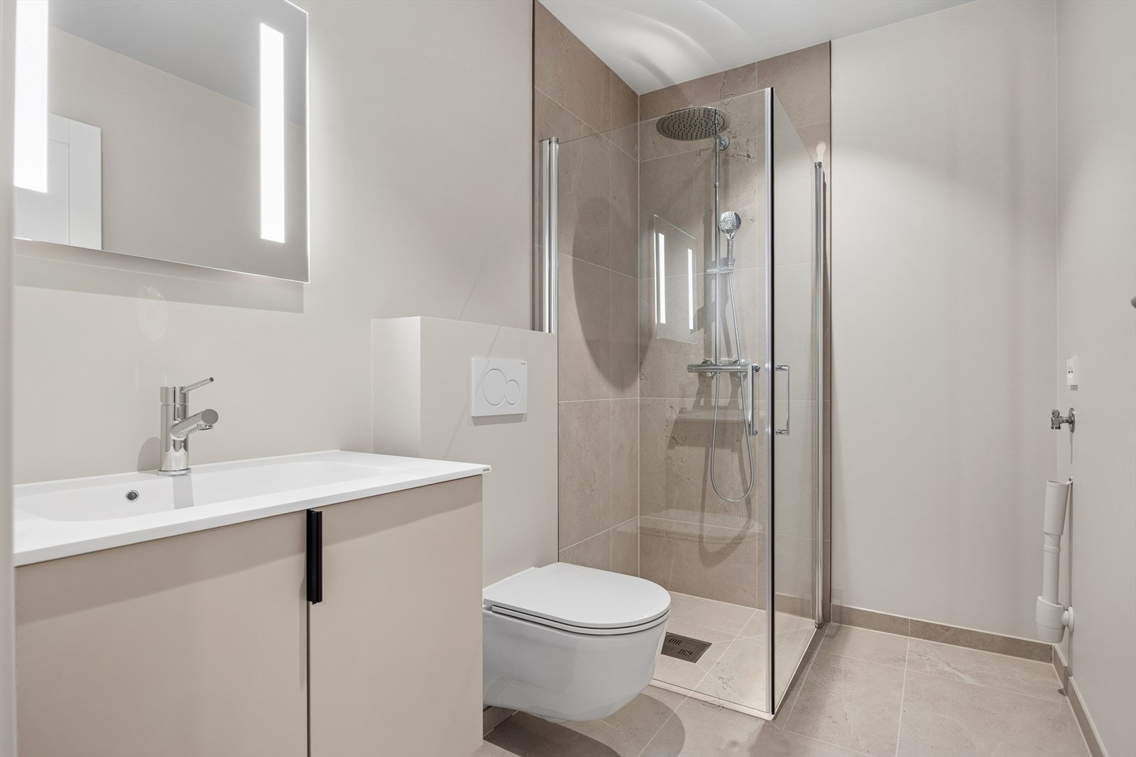 Badet har malte overflater, flis på gulv og flislagte vegger i dusjsonen, og er innredet med dusjhjørne, toalett og servant. Galleribilde