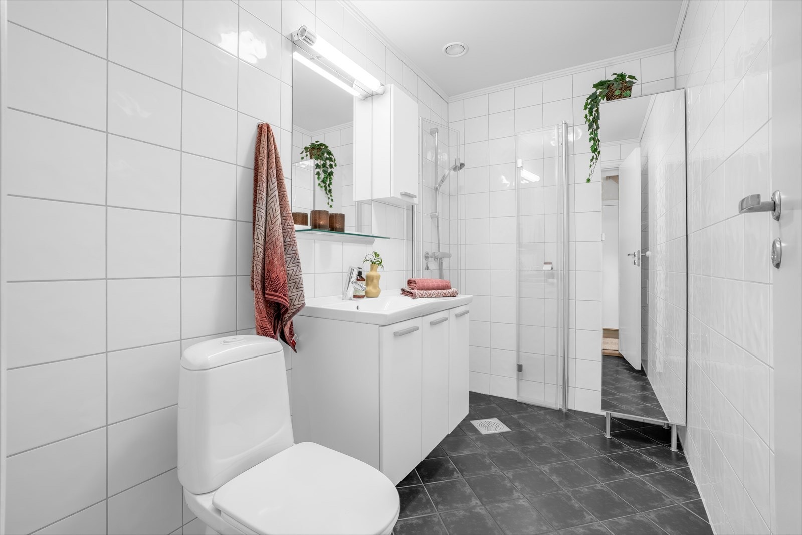 Flislagt baderom i 1. etasje, utstyrt med gulvstående toalett, dusjhjørne og servantinnredning. Galleribilde