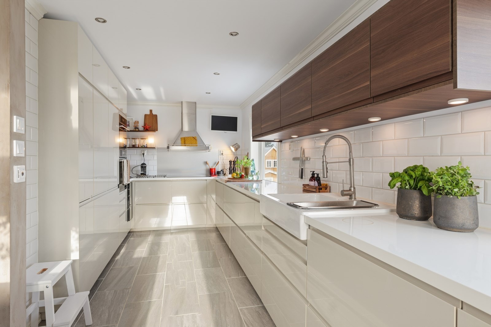 Innredningen har glatte fronter som gir et rent og tidløst uttrykk, mens benkeplaten i laminat er både praktisk og slitesterk. Over benkeplatene er veggene kledd med fliser, som både hever det estetiske inntrykket og gjør rengjøringen enkel. Galleribilde