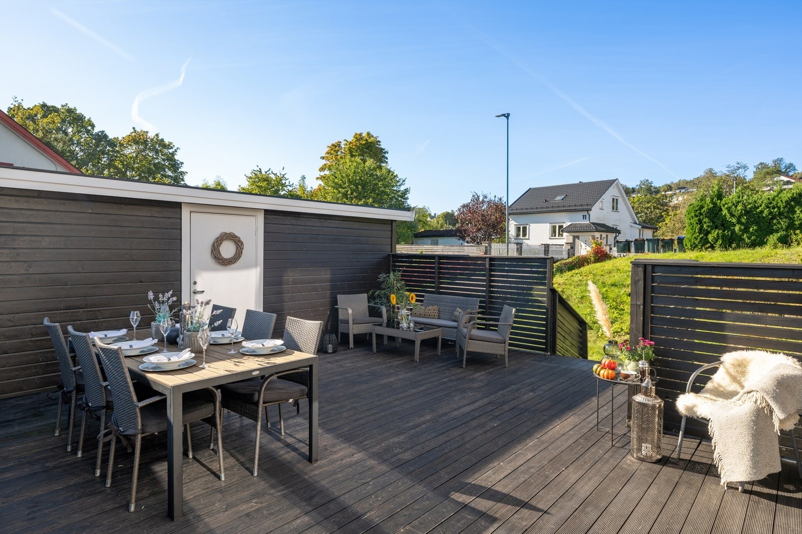 En solid tretrapp leder deg videre ned til den skjermede hagen på baksiden av boligen, som gir en naturlig forlengelse av uteområdet og gjør det enkelt å bevege seg mellom terrasse og hage. Galleribilde