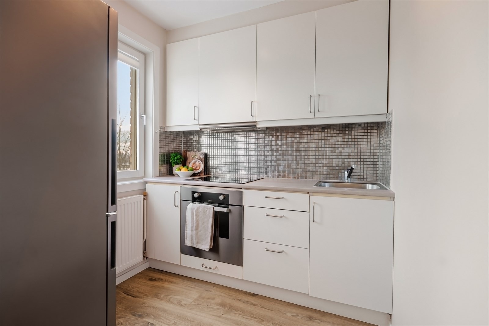 Lyst kjøkken med integrert stekeovn og plateopp. Galleribilde