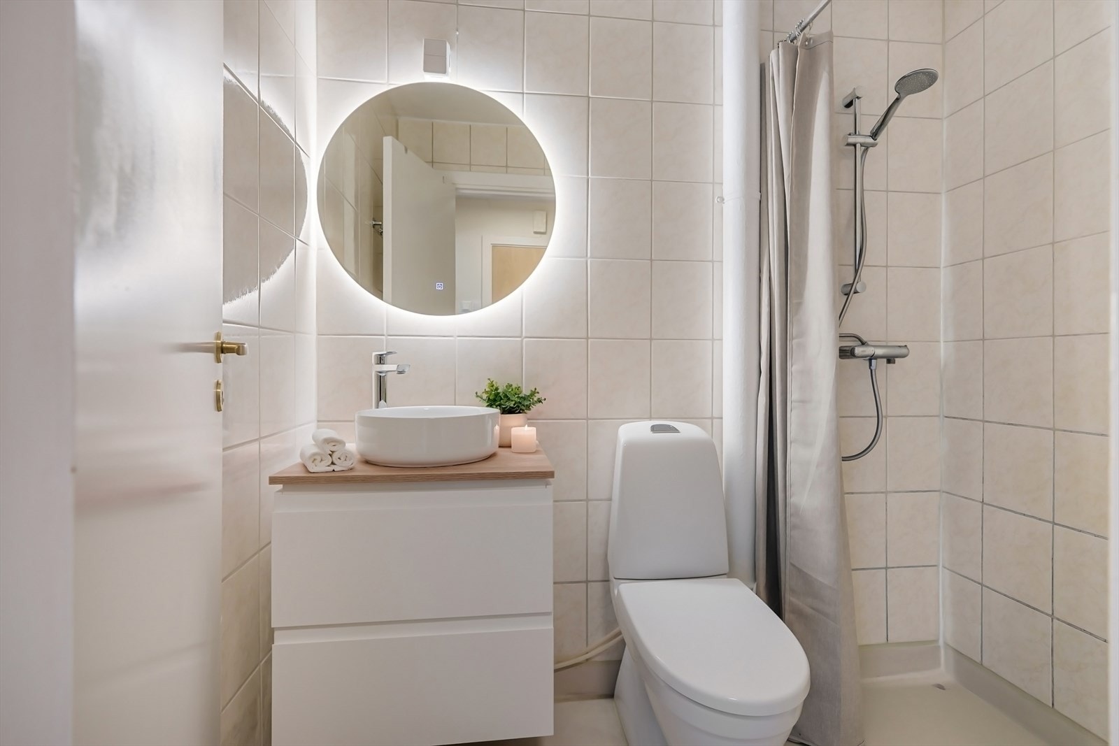 Bad med lyse overflater, servant med skuffer, ledspeil, toalett og dusj. Galleribilde