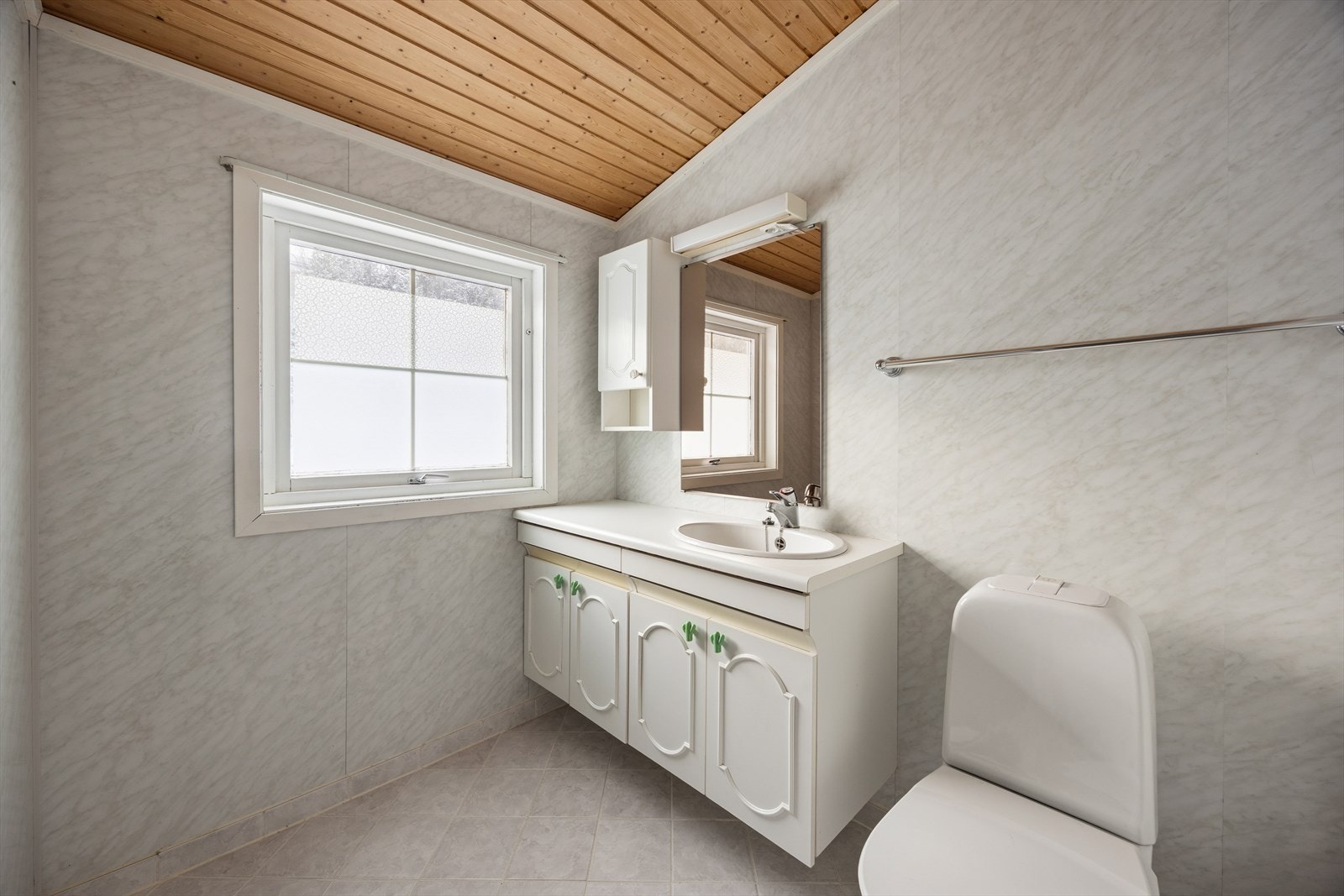 Badet på loftet har baderomsplater på veggene, panel i himlingen og fliser på gulvet. Galleribilde