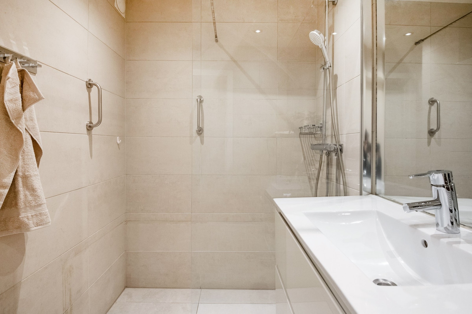 Romslig dusjnisje med glassvegg og vegghengt armatur. Galleribilde