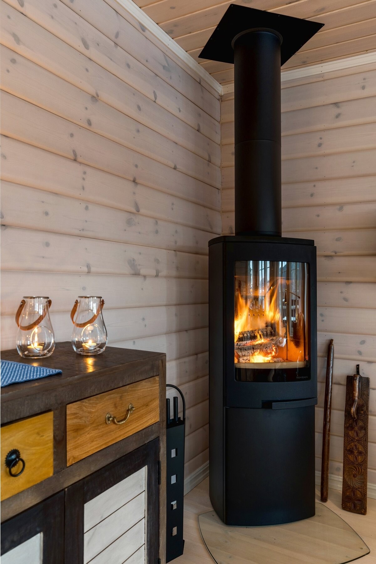 I stuen er det i tillegg til panelovner og varmepumpe montert en moderne peisovn fra Nordpeis som varmer godt på sene høst- og vinterkvelder samtidig som den også utgjør et pent møbel, som bidrar til den lune hyttefølelsen man ønsker på fjellet. Galleribilde