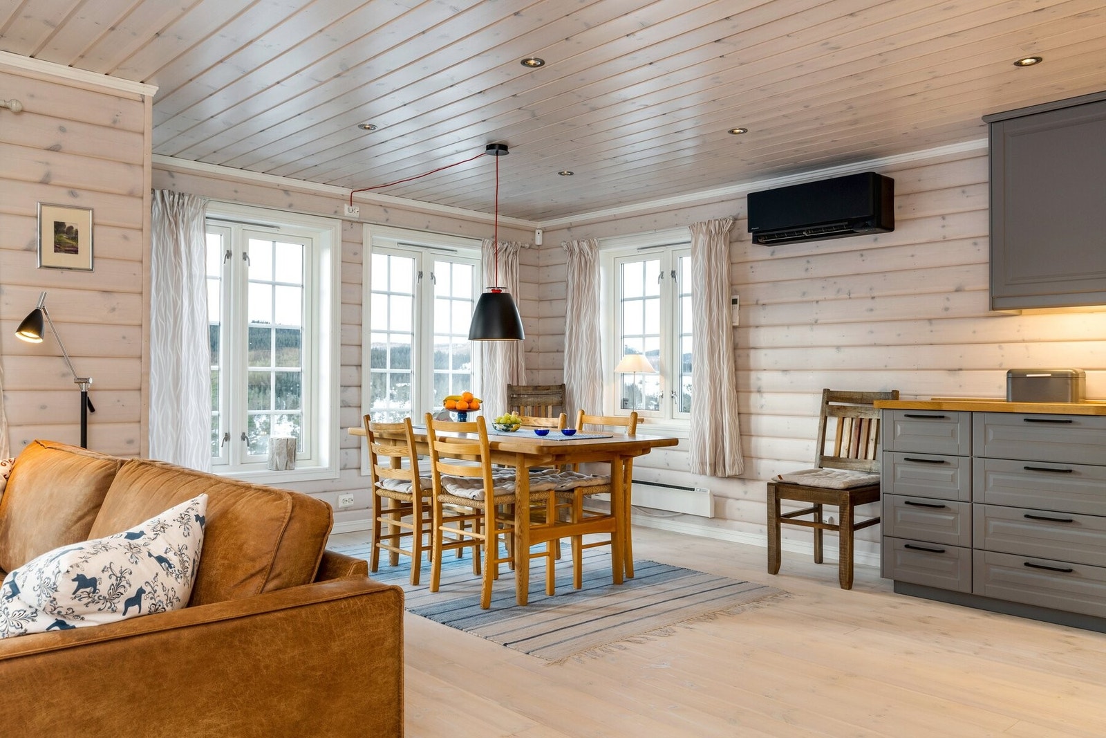 Stue, spisestue og kjøkken i åpen løsning som gjør dette til et sosialt rom og et naturlig samlingspunkt i hytta. Galleribilde