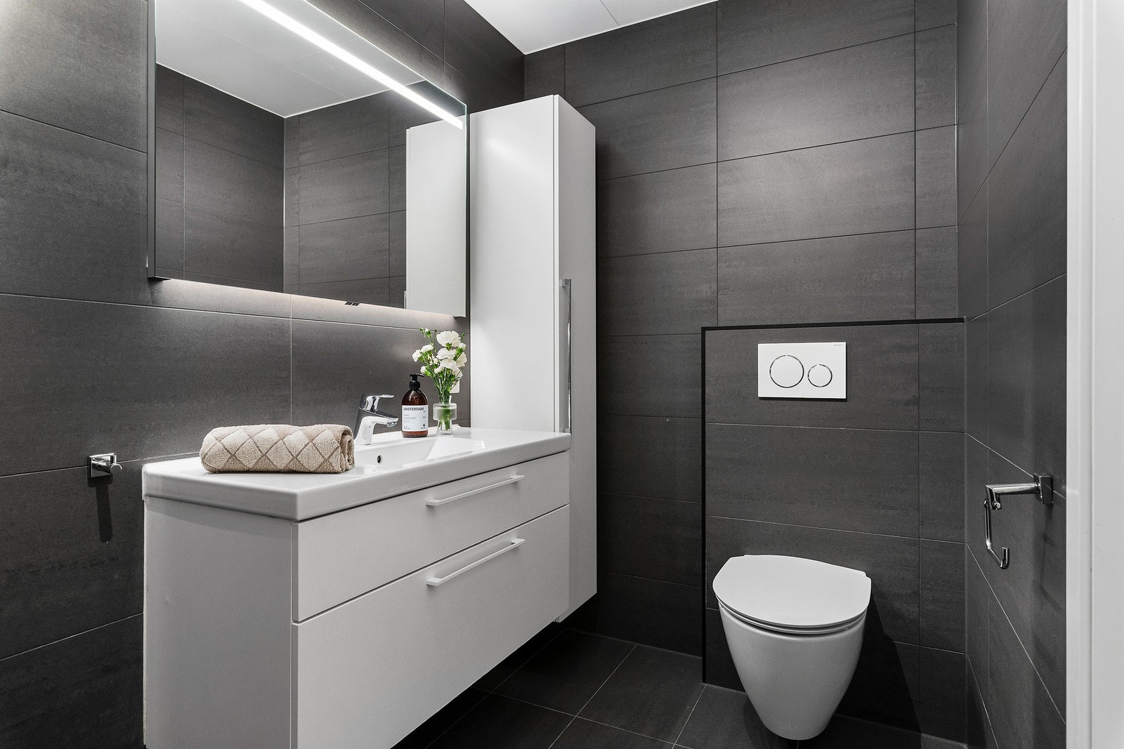 Bad i utleiedel har vegghengt wc og lyssatt speil over servant. Servantinnredning både med skuffer og høyskap. Galleribilde