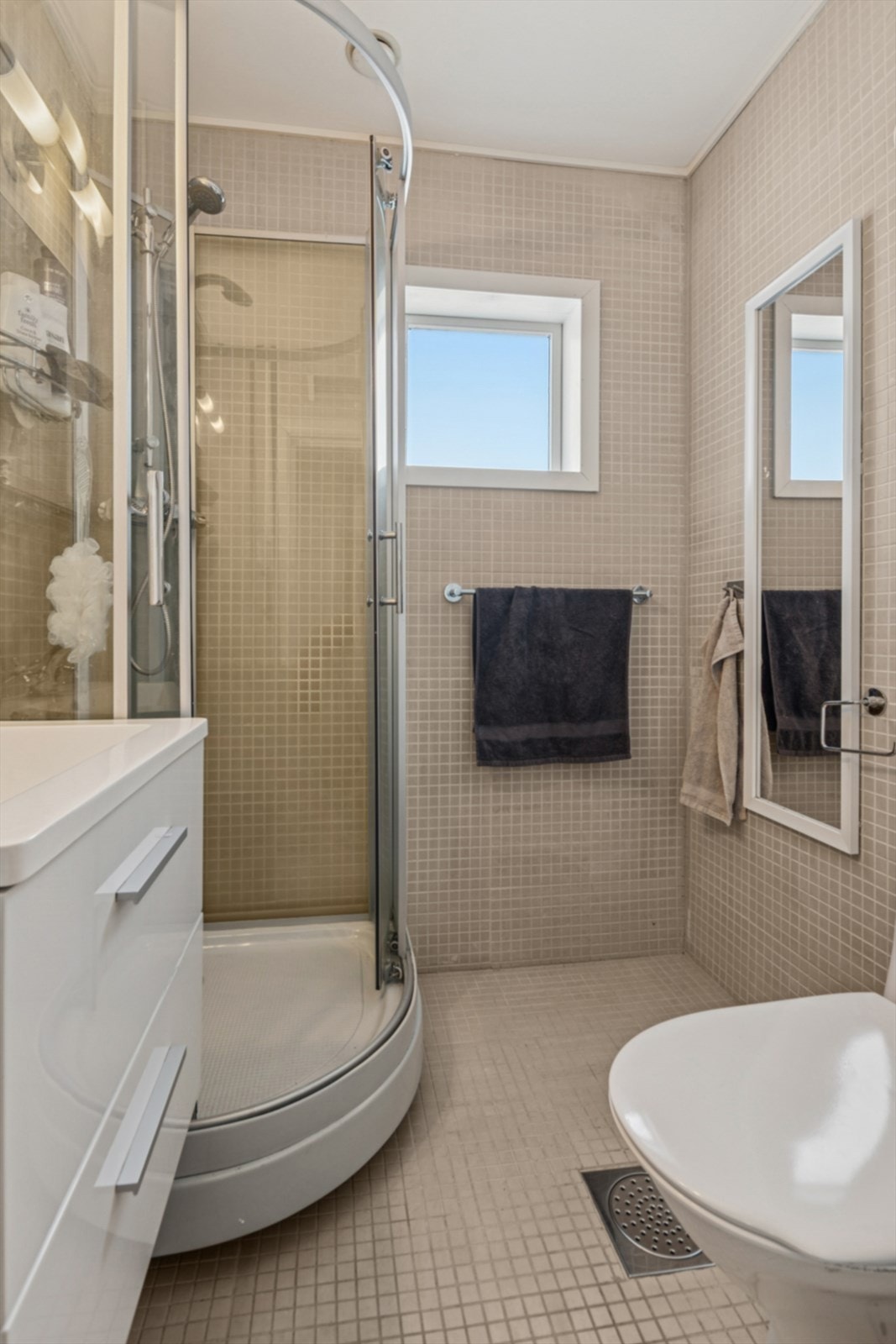 Flislagt bad i første etasje utstyrt med dusjkabinett, toalett og moderne baderomsinnredning. Det er varmekabler i gulv. Galleribilde