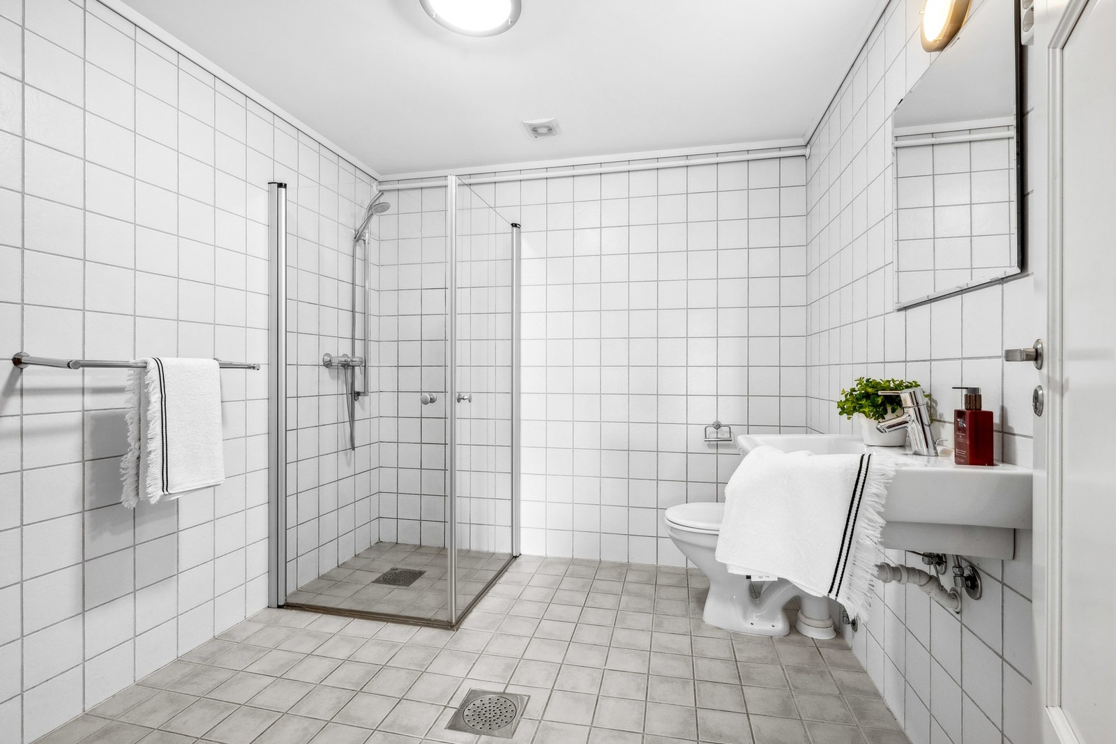 Flislagt bad med varmekabler i gulv, servant, dusjhjørne og wc. Galleribilde