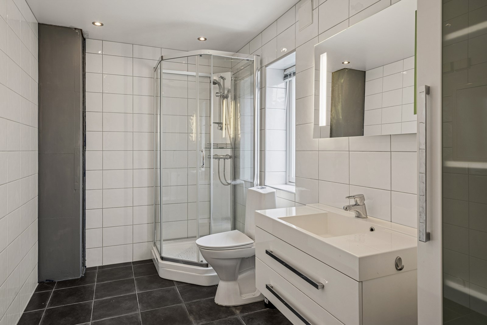 Flislagt bad med tidløst preg i første etasje, med elektrisk gulvvarme for økt komfort. Galleribilde