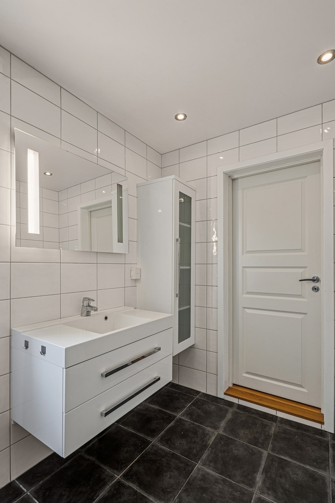 Baderomsinnredning med heldekkende servant, speil og innfelte downlights i taket. Galleribilde