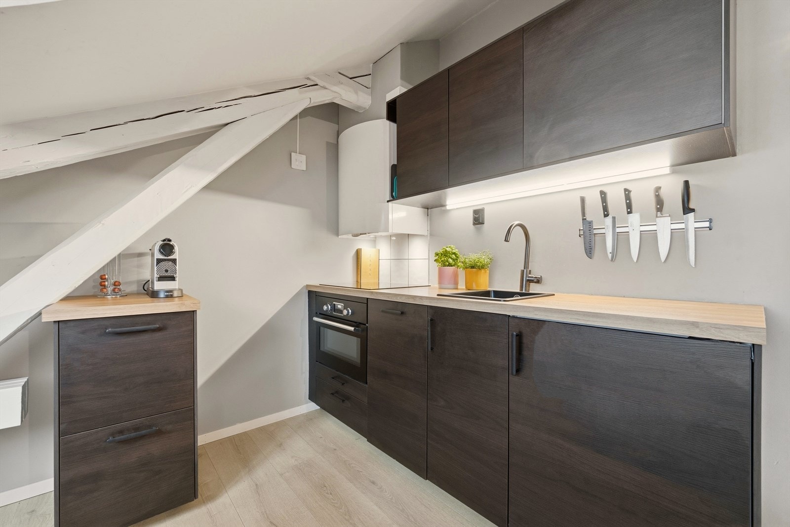 Kjøkkenet har glatte fronter, flislagt over platetopp og benkeplate i laminat Galleribilde