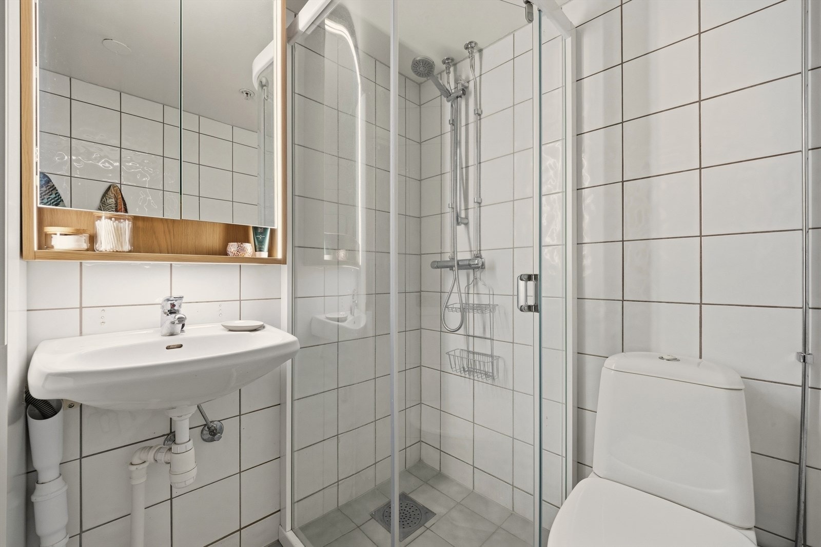 Videre er badet utstyrt med servant, toalett, samt vegghengt speil og dusjhjørne/vegger fra 2025 Galleribilde