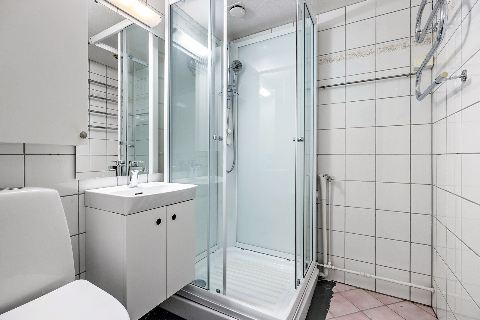 Badet er utstyrt med dusjkabinett, servant med underskap, speil med overlys, veggskap, høyskap, toalett og opplegg for vaskemaskin. Galleribilde